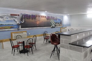 Un restaurante con un mural, zona de bar y mesas.
