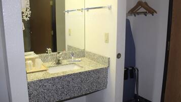 Un baño con lavamanos de encimera de granito, un espejo y un perchero para toallas.