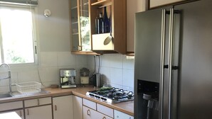 Eine Küche mit Kühlschrank, Herd, Spüle und Schränken.