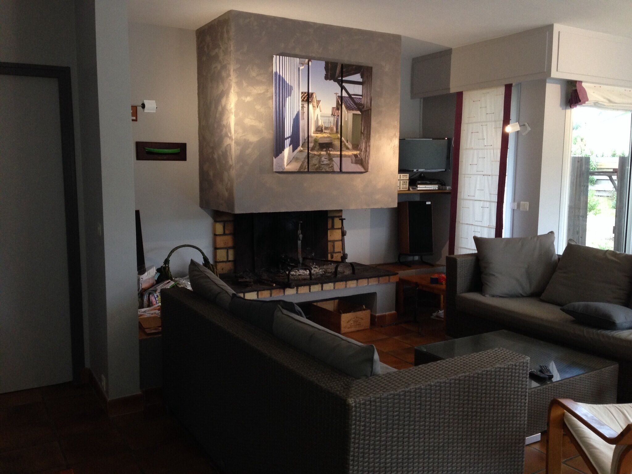 A living room with a fireplace, a sofa, a television, and a window with curtains.