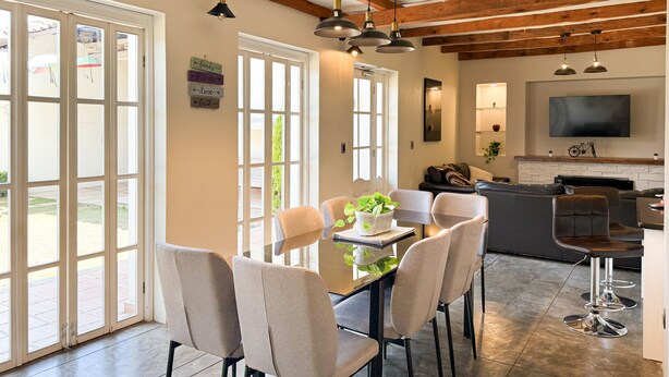 A dining area with a glass table, four chairs, and pendant lights. There is a kitchen area with a TV and a bicycle on the wall. - NICE HOUSE ONLY 5 STREETS FROM THE CITY CENTER (Col Centro Cuatilulco)