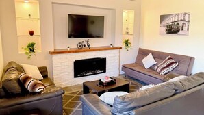 A modern living room with a fireplace, leather sofas, a flat-screen TV, and a mounted picture of a building. - NICE HOUSE ONLY 5 STREETS FROM THE CITY CENTER (Col Centro Cuatilulco)