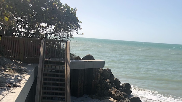 A beach with a concrete walkway, a wooden staircase, and a rocky outcrop. - Best Value on Manasota Key and Steps to Lemon Bay (Englewood)
