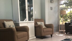 A living room with two brown armchairs, a white cabinet, and a blue patterned rug. - Best Value on Manasota Key and Steps to Lemon Bay (Englewood)