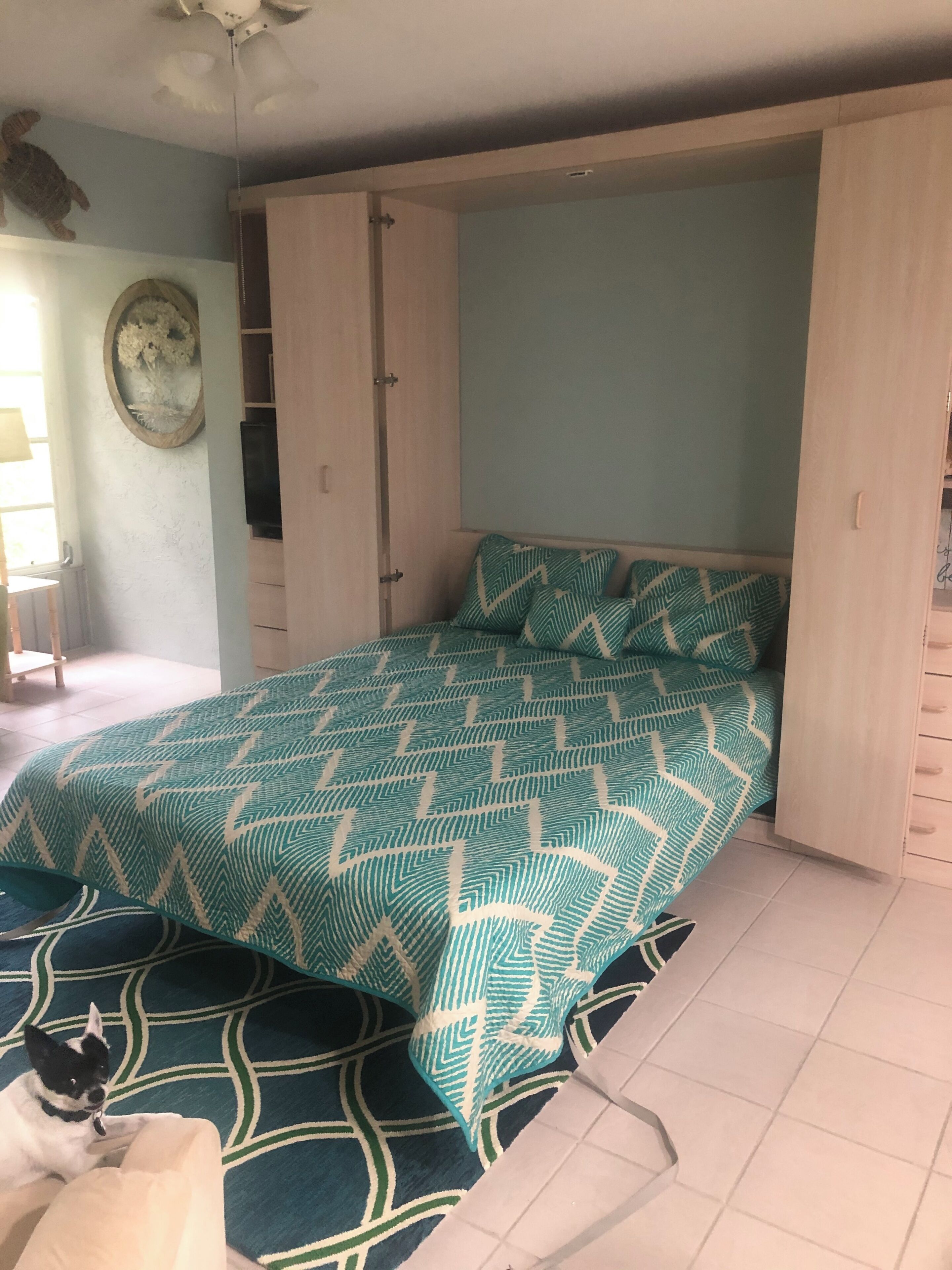 Een slaapkamer met een bed, een hond en een kledingkast.