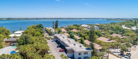 Vista aérea de una zona residencial costera con un edificio grande que tiene varios espacios de estacionamiento y una piscina.