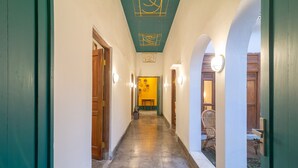 A hallway with green doors, a tiled floor, and a chandelier. - Wonderloft Hostel Jogja (Yogyakarta)
