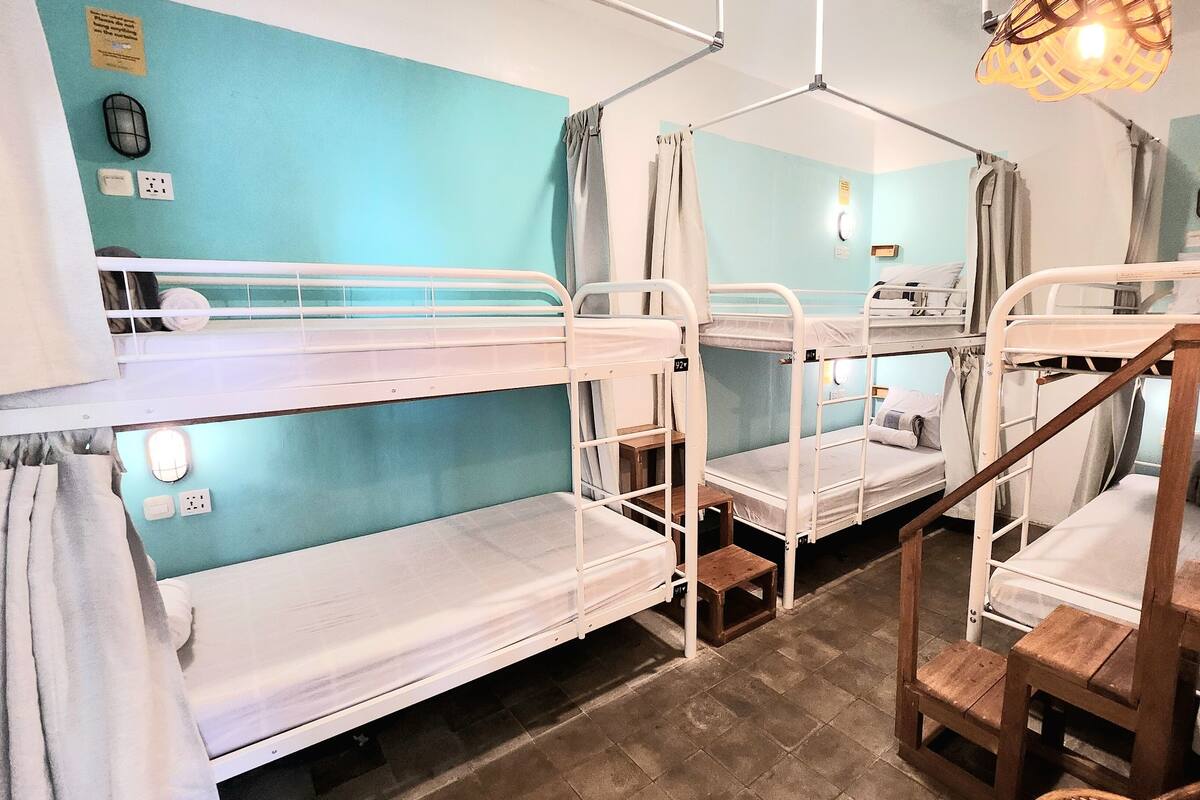 A room with bunk beds, a wooden chair, a small table, and a ceiling light fixture.