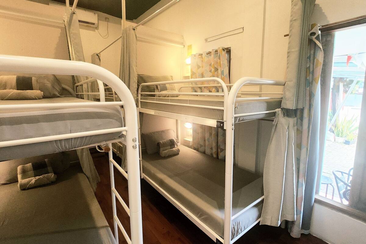 A bunk bed room with a window, a small table, and a wall-mounted air conditioning unit.