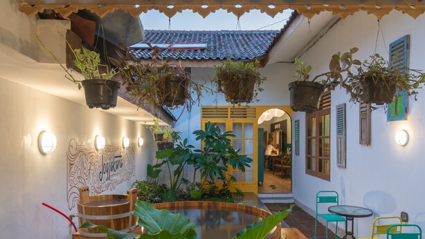 A courtyard with a wooden water feature, hanging plants, and outdoor seating. - Wonderloft Hostel Jogja (Yogyakarta)