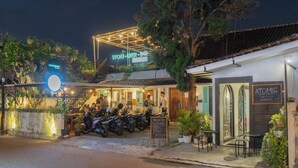 A restaurant with outdoor seating, a neon sign, and parked motorcycles. - Wonderloft Hostel Jogja (Yogyakarta)