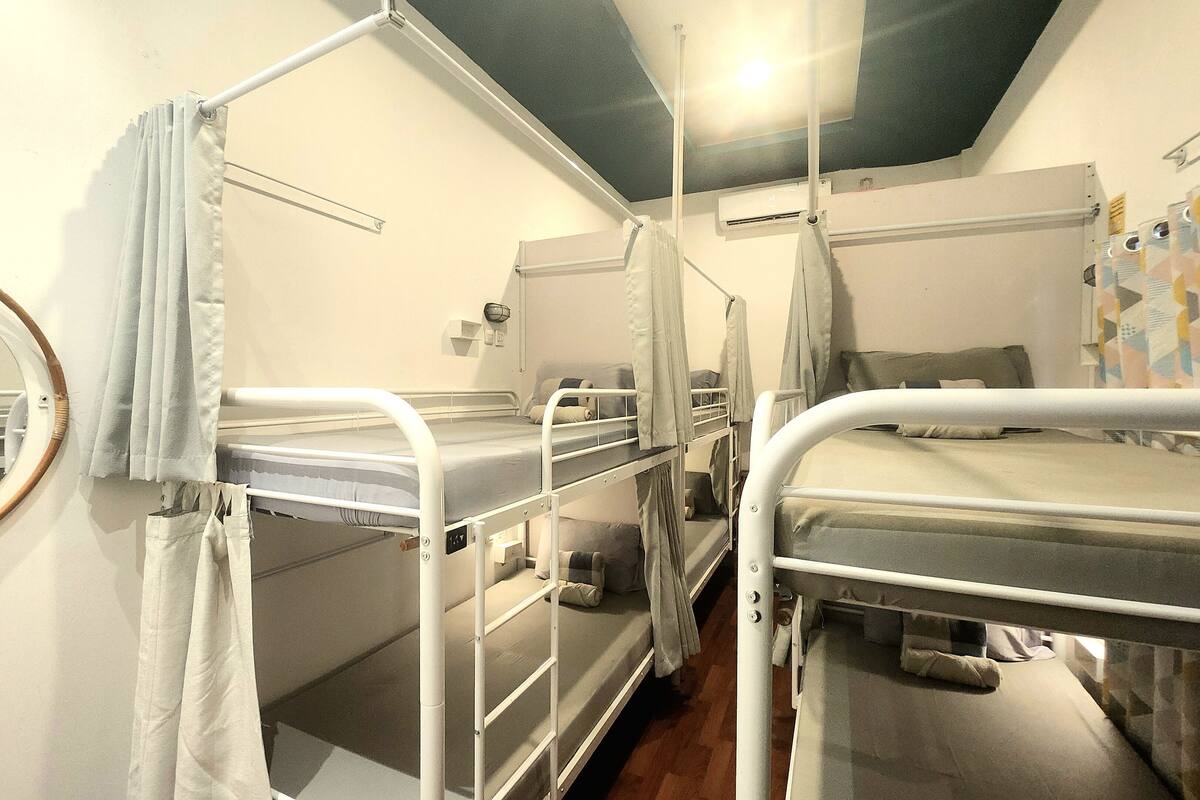 A dormitory room with bunk beds, a round mirror, and a ceiling light.
