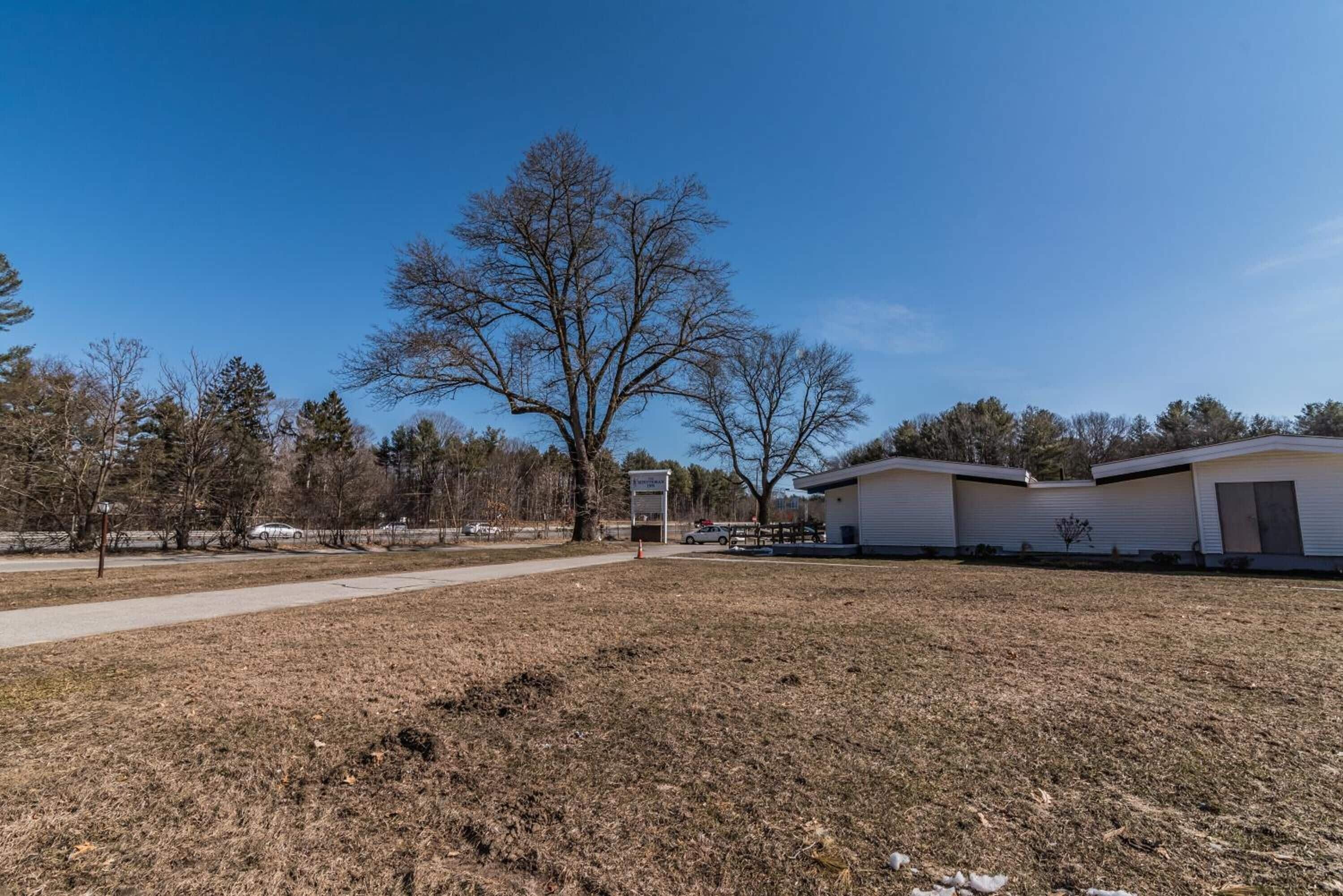 A grassy area with a pathway leading to a row of mobile homes.