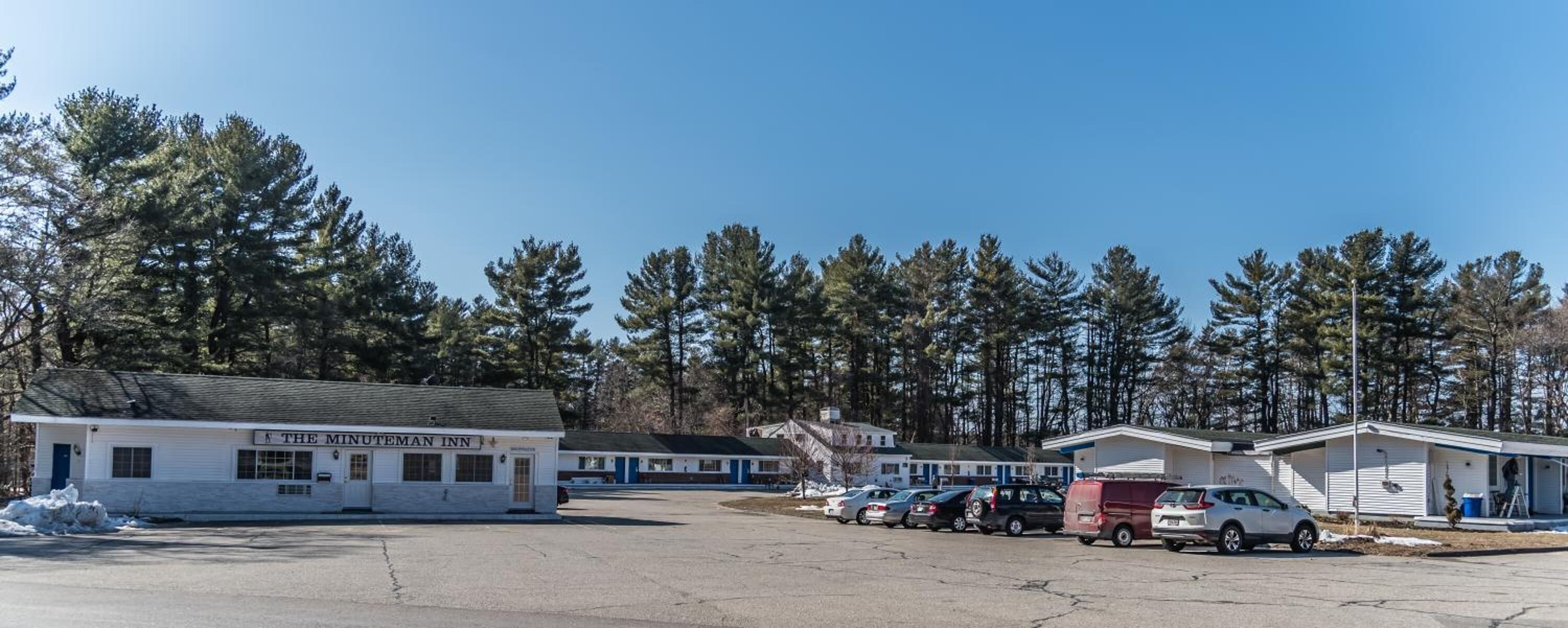 The Minuteman Inn with a parking lot and several vehicles.