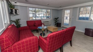 A room with red upholstered seating, a glass table, and large windows. - Howard Johnson by Wyndham Acton (Acton)