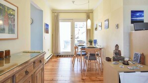 A room with a wooden floor, a dining table with chairs, a cabinet, and a Buddha statue. - Gorgeous Patio and Deck w/ Central AC! (Provincetown)