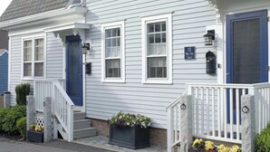A two-story house with a blue front door, white trim, and a small porch with a stone railing. - Gorgeous Patio and Deck w/ Central AC! (Provincetown)