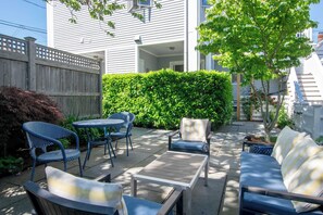A patio with outdoor furniture, a wooden fence, and a hedge. - Gorgeous Patio and Deck w/ Central AC! (Provincetown)
