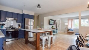A modern kitchen with dark blue cabinets, a stainless steel refrigerator, and a wooden island with stools. - Perfect for Group w/ Kids & Dogs w/ Hot Tub (Chatham)