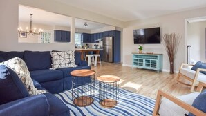 A modern living room with a blue sofa, two coffee tables, and a striped rug. - Perfect for Group w/ Kids & Dogs w/ Hot Tub (Chatham)