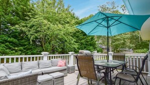 A deck with outdoor furniture, including a sofa, chairs, and a table with an umbrella. - Perfect for Group w/ Kids & Dogs w/ Hot Tub (Chatham)