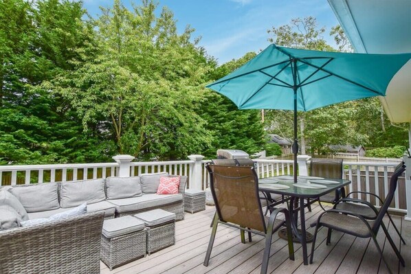 A deck with outdoor furniture, including a sofa, chairs, and a table with an umbrella.