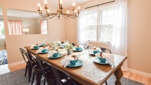A dining room with a wooden table set for six, six chairs, a chandelier, and a window with curtains. - Perfect for Group w/ Kids & Dogs w/ Hot Tub (Chatham)