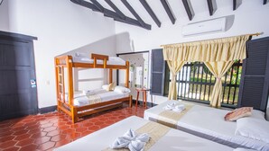 Habitación de hotel con dos camas, una litera de madera, suelo de baldosas, una ventana con cortinas y un equipo de aire acondicionado.