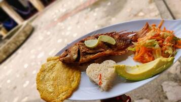 Ein Teller mit gebratenem Fisch, Reis, Avocado und einem gemischten Salat.