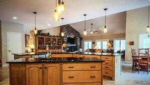 Een ruime keuken met een groot kookeiland, houten kastjes en hanglampen.