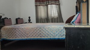 Ein Schlafzimmer mit Bett, Klimaanlage, einem Fenster mit Vorhängen und einem Schminktisch.