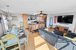 A modern kitchen with wooden cabinets, a central island, and a dining area with a table set for four.