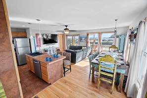 A spacious living area with a kitchen, dining table, and a large TV.