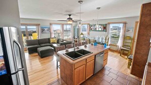 Een moderne keuken met een centraal eiland, houten kastjes en een groot raam met uitzicht op de stad.