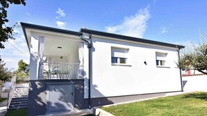 Una casa a due piani con un balcone, un garage e un piccolo giardino.