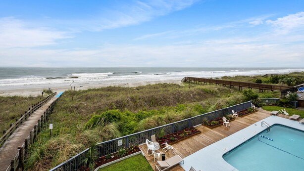 A pool area with a view of the beach and ocean. - Spacious and newly updated 2nd floor walk-up + Free Attraction Tickets! (North Myrtle Beach)