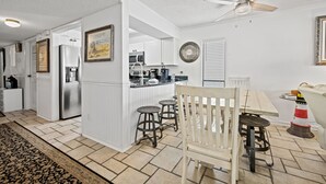 A modern kitchen with white cabinetry, a central island, and bar stools. - Spacious and newly updated 2nd floor walk-up + Free Attraction Tickets! (North Myrtle Beach)