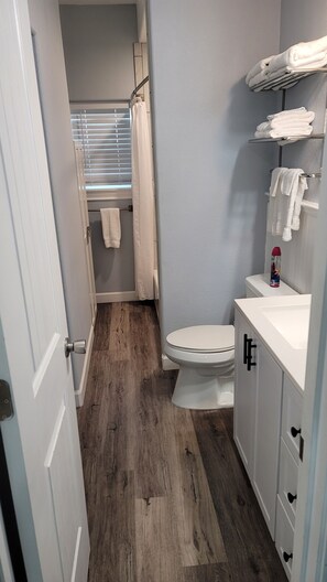 Une salle de bain équipée d’un WC, d’un lavabo, d’un porte-serviettes et d’un rideau de douche.