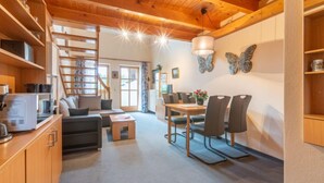 A cozy interior with a wooden ceiling, a dining area with chairs, a sofa, and a staircase leading to another level. - Am Hohen Bogen by Interhome (Arrach)