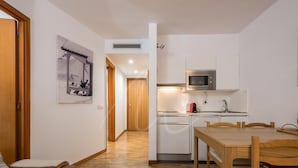 A compact kitchen with a microwave, sink, and wooden dining table. - Bonaigua 006 (Baqueira)
