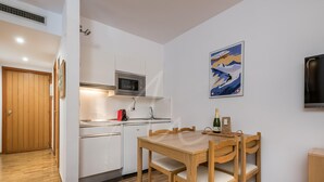 A compact kitchen with a microwave, sink, and wooden dining table with chairs. - Bonaigua 006 (Baqueira)