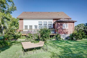 A two-story house with a garage, a deck, and a well-maintained garden.
