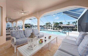 Ein überdachter Außenbereich mit Pool, Sitzgelegenheiten und Blick auf die Umgebung.