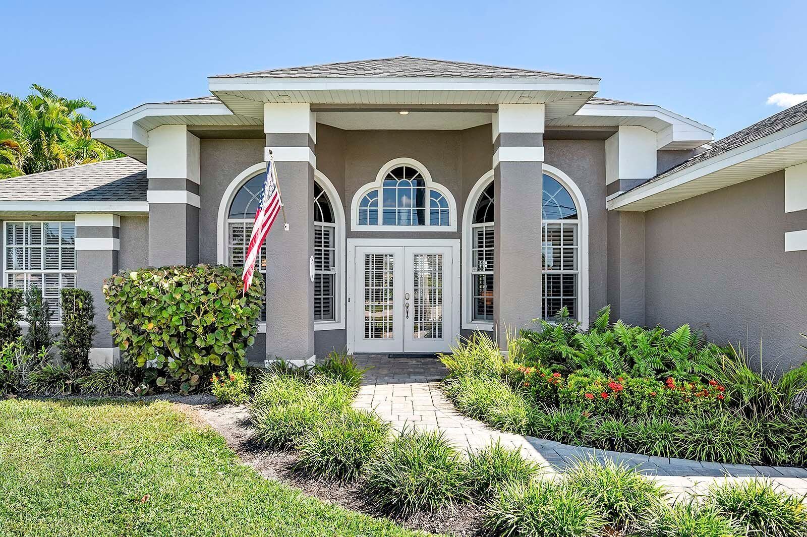 A two-story house with a central entrance, a covered porch, and a flag.