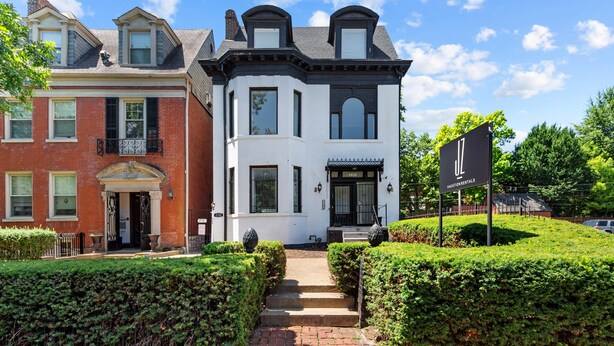 A two-story building with a black and white facade, a prominent entrance with steps, and a sign indicating "ULocation Rentals." - Historic 3BR Near Barnes Jewish Hospital | Walkable CWE | Dog-Friendly (St Louis)
