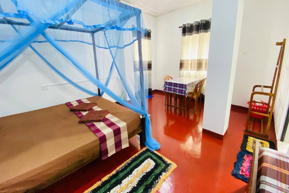 A room with a bed, a dining area, and a chair.