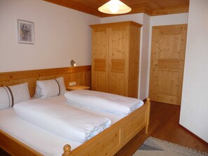 Ein Doppelbett mit Holz-Kopfstück, ein Nachttisch, eine Wandlampe und Holzschränke.