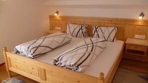 Una cama doble con cabecera de madera, dos mesitas de noche y un tocador con lámpara.
