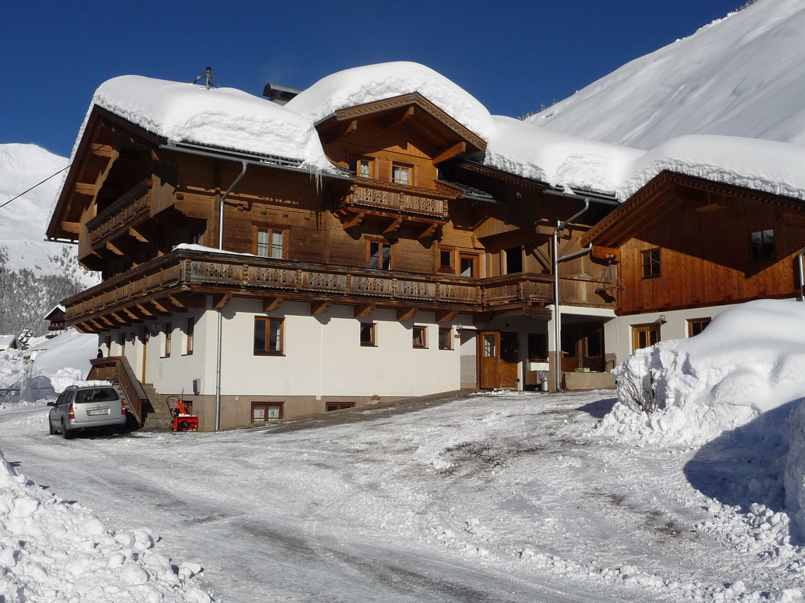 A wooden chalet with a balcony, surrounded by snow-covered mountains.