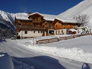 Eine Holzhütte mit Balkon, einer Seilbahn und einem verschneiten Berg im Hintergrund.